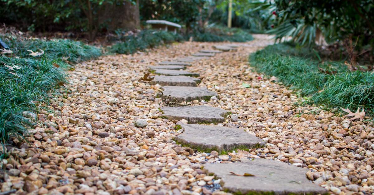 A walkway with square paver stones in the center and a variety of pebbles in shades tan, brown, and white.