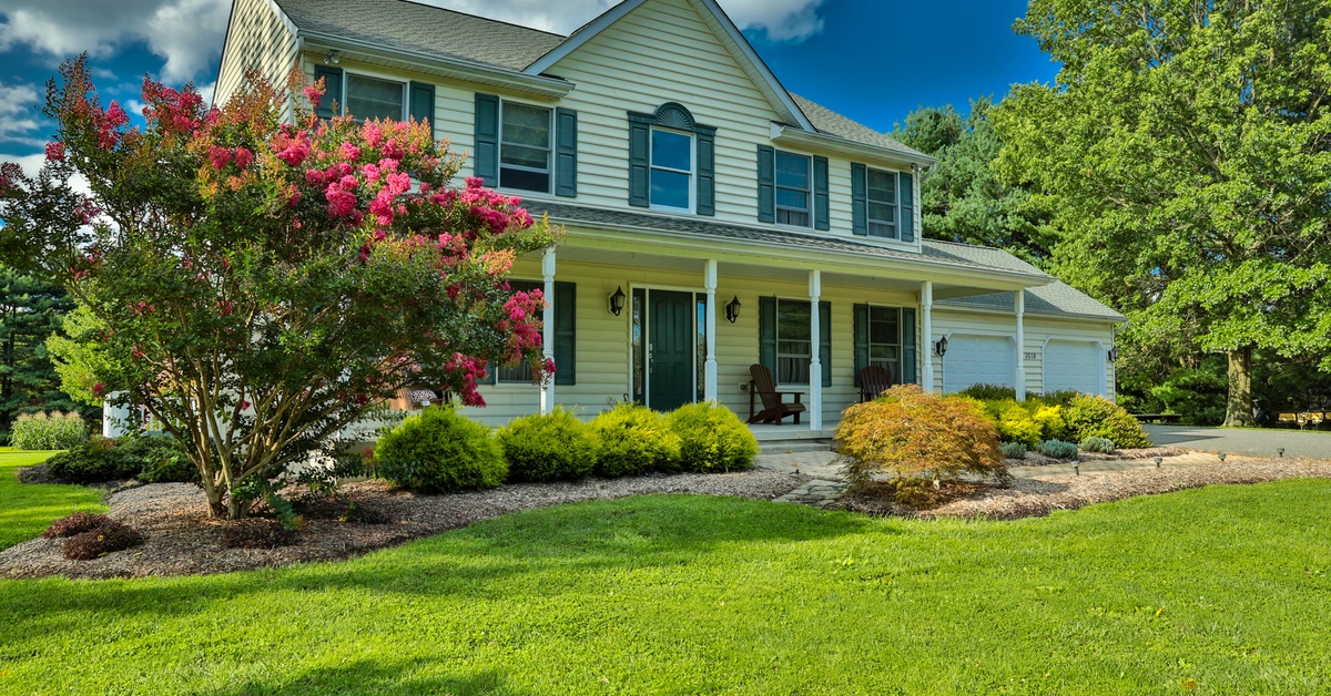 A Idaho home with freshly groomed grass and beautiful landscaping near the front porch with ground cover and shrubs.