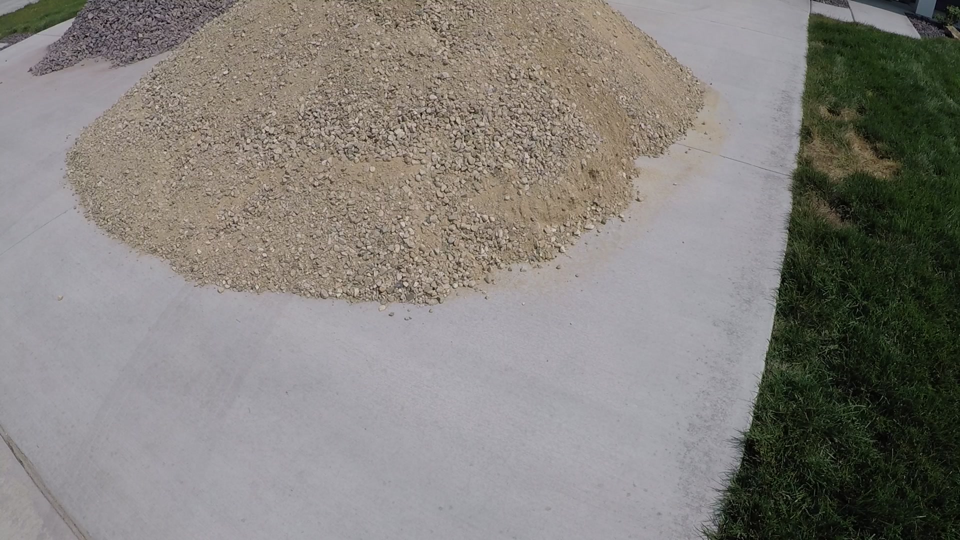 A delivered pile of gravel on a residential driveway